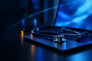 Stethoscope resting on a laptop keyboard with blue light reflections, symbolizing digital health or diagnostics.